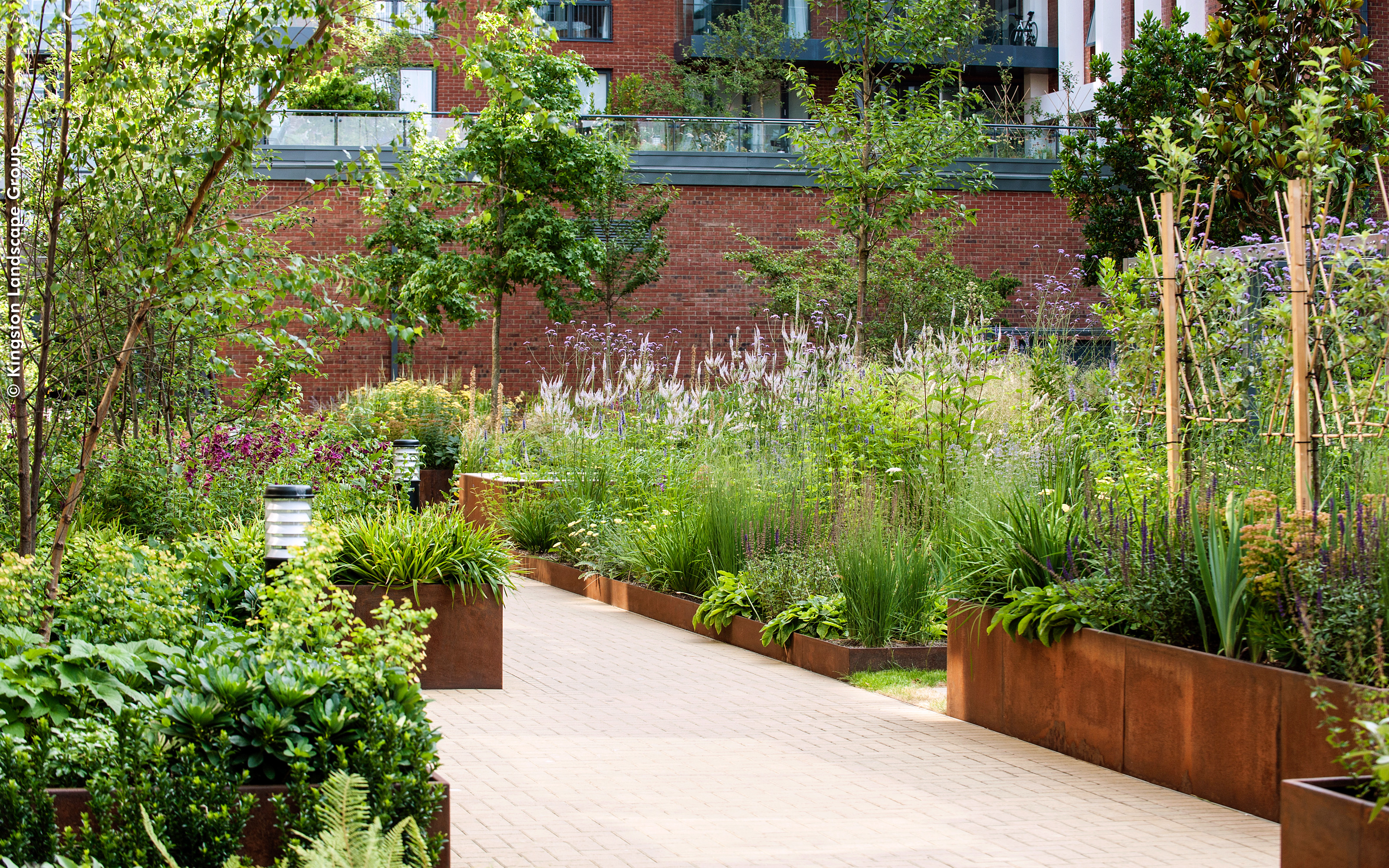 Large planters with a variety of flowers along a pathway