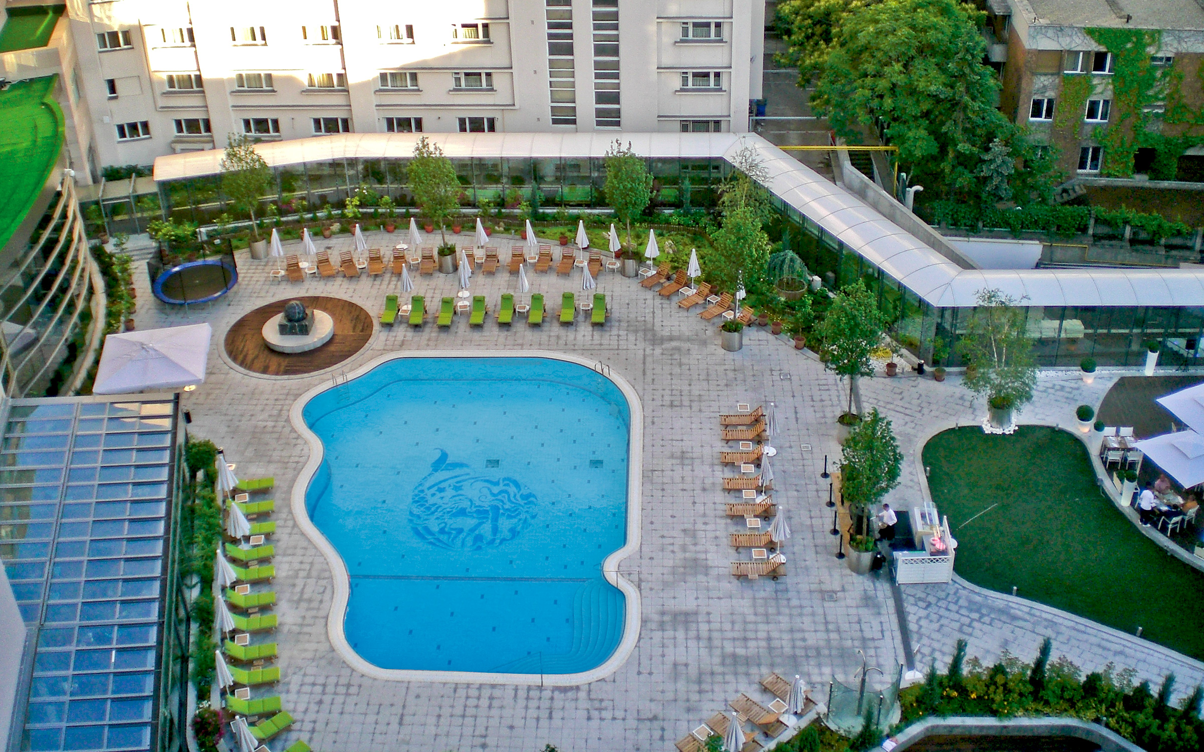 Bird's eye view onto a courtyard with sun beds and a swimming pool