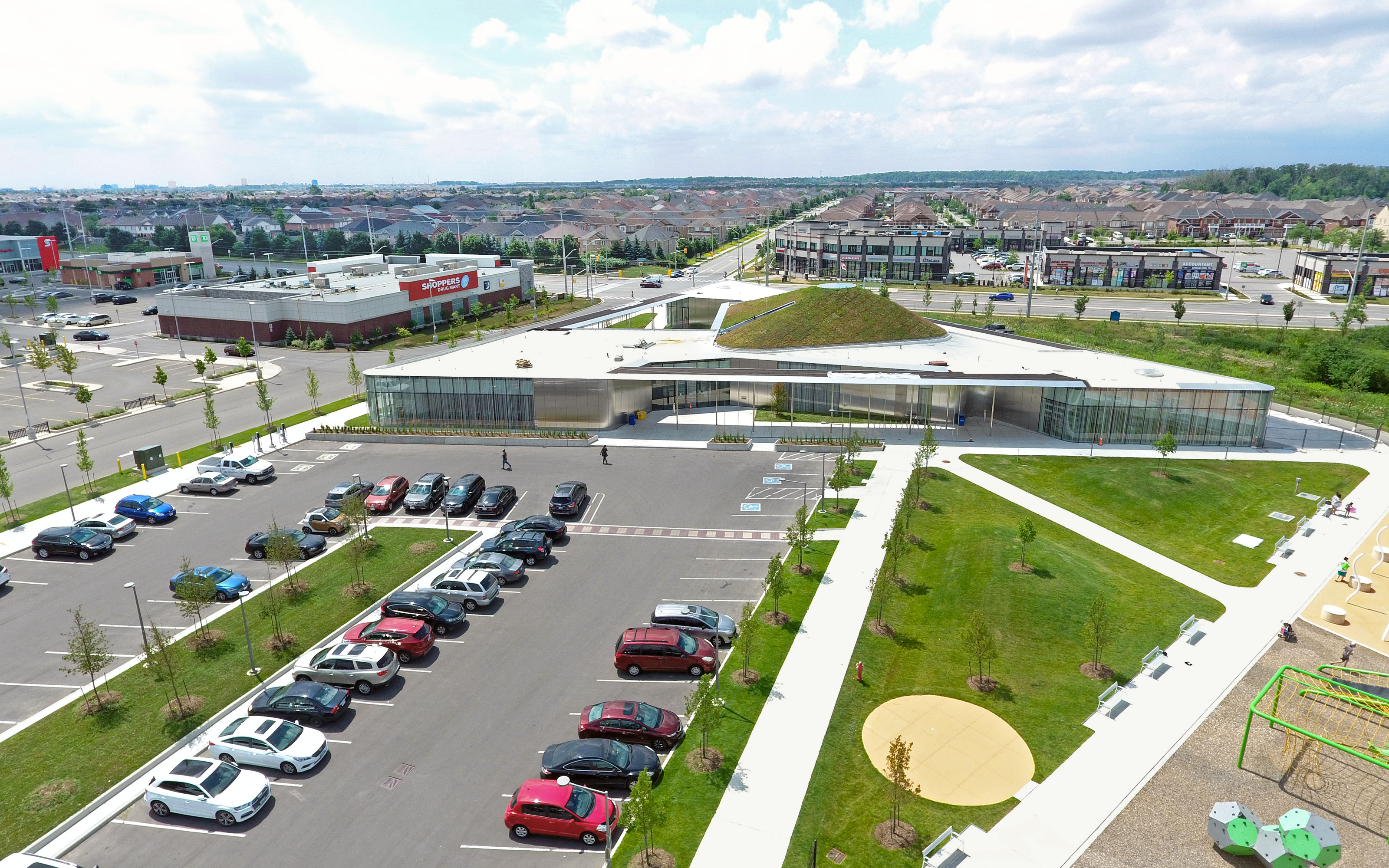 Large parking area in front of a building with pitched green roof