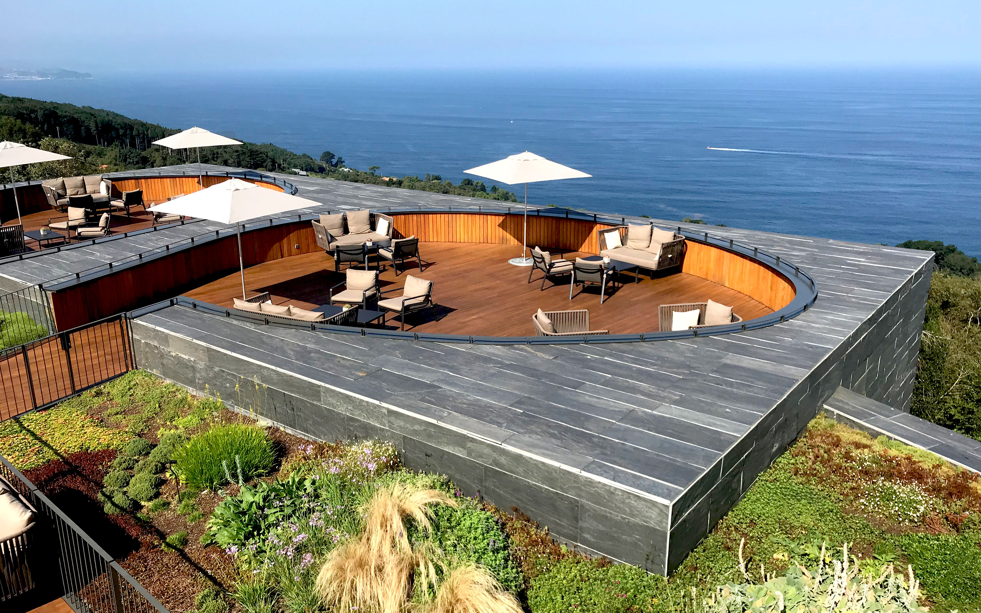 Bird's eye view onto terraces surrounded by vegetation and a view onto the ocean