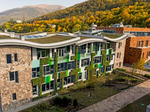 Building with natural stone façade, vertical greening and wavelike green roofs