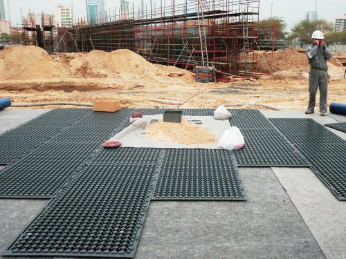 Worker laying out Stabilodrain® mats on the building site 