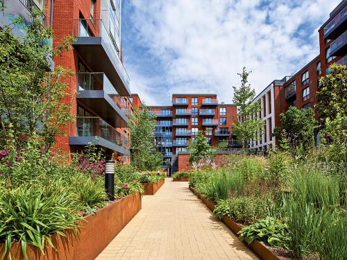 Courtyard with blooming plant beds and a pathway surrounded by residential buildings