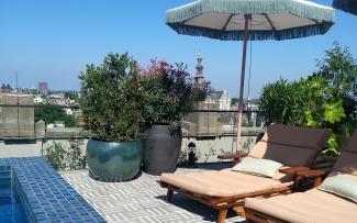 The hallmark of Soho House is on display even on the rooftop, creating a harmonious coming together of various different colours and patterns. © ZinCo Benelux B.V. Roof terrace with deck chairs, parasols, plant planters and a swimming pool