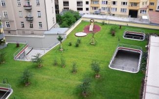 Vegetated underground garage with lawn, small trees and playground