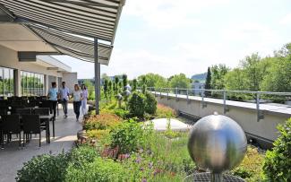 Whether a building is new or is to be refurbished, the potential inherent in all of these roofs can be comprehensively exploited with green roofing. People on a roof garden with water feature and sitting area