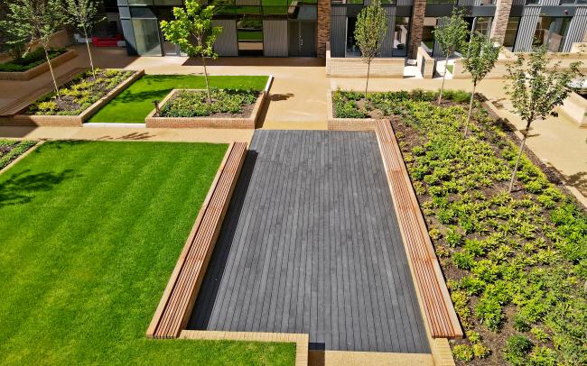 Courtyard with a podium deck, lawn, wooden benches and small trees